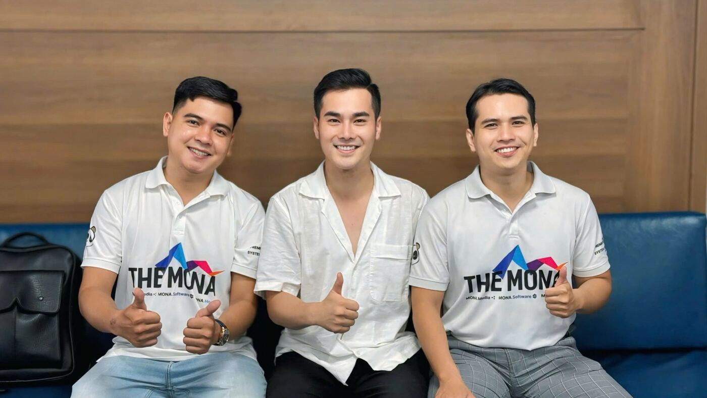 Nhân viên MONA mặc áo polo THE MONA chụp ảnh cùng khách hàng